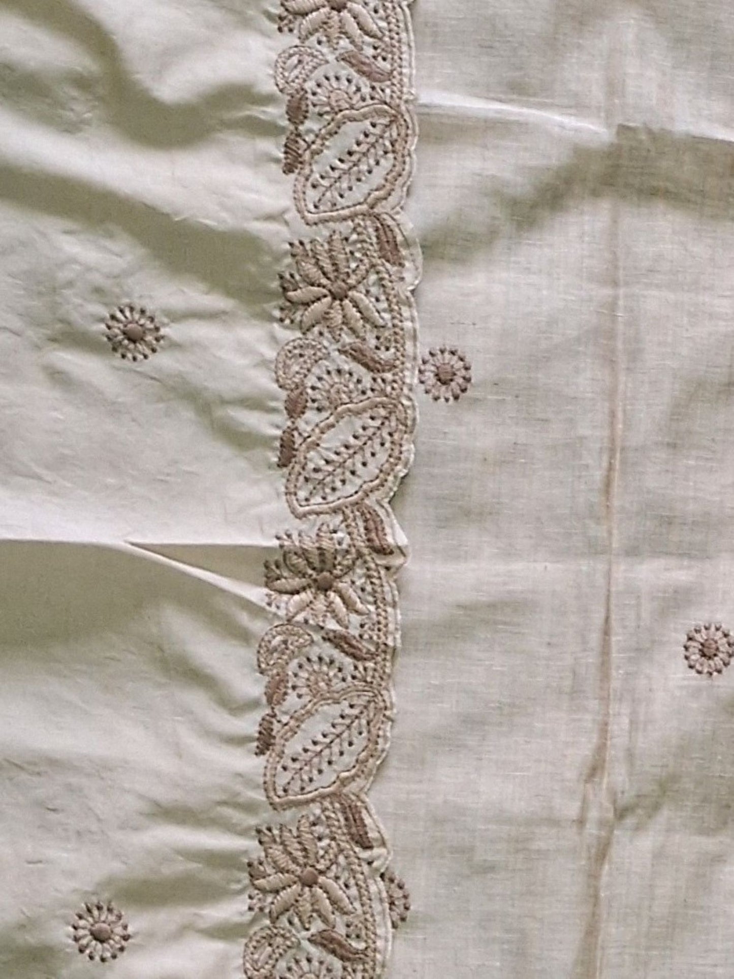 Close-up of a ivory beige khadi chandri fabric with an embroidered border and small scattered floral motifs showing of a dupatta.