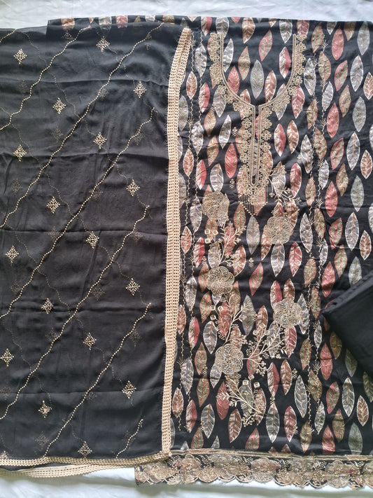 A black turkish cotton unstitched dress material with a gold stone work and a patterned work  featuring gold, pink, and beige paisley motifs.